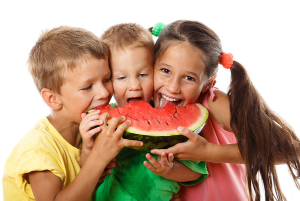 Drei Kinder essen ein Stück einer Wassermelone.