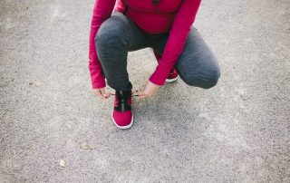 Schwangere Frau bindet sich ihre Laufschuhe