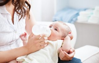 Mutter füttert Baby mit Fläschchen mit Säuglingsnahrung