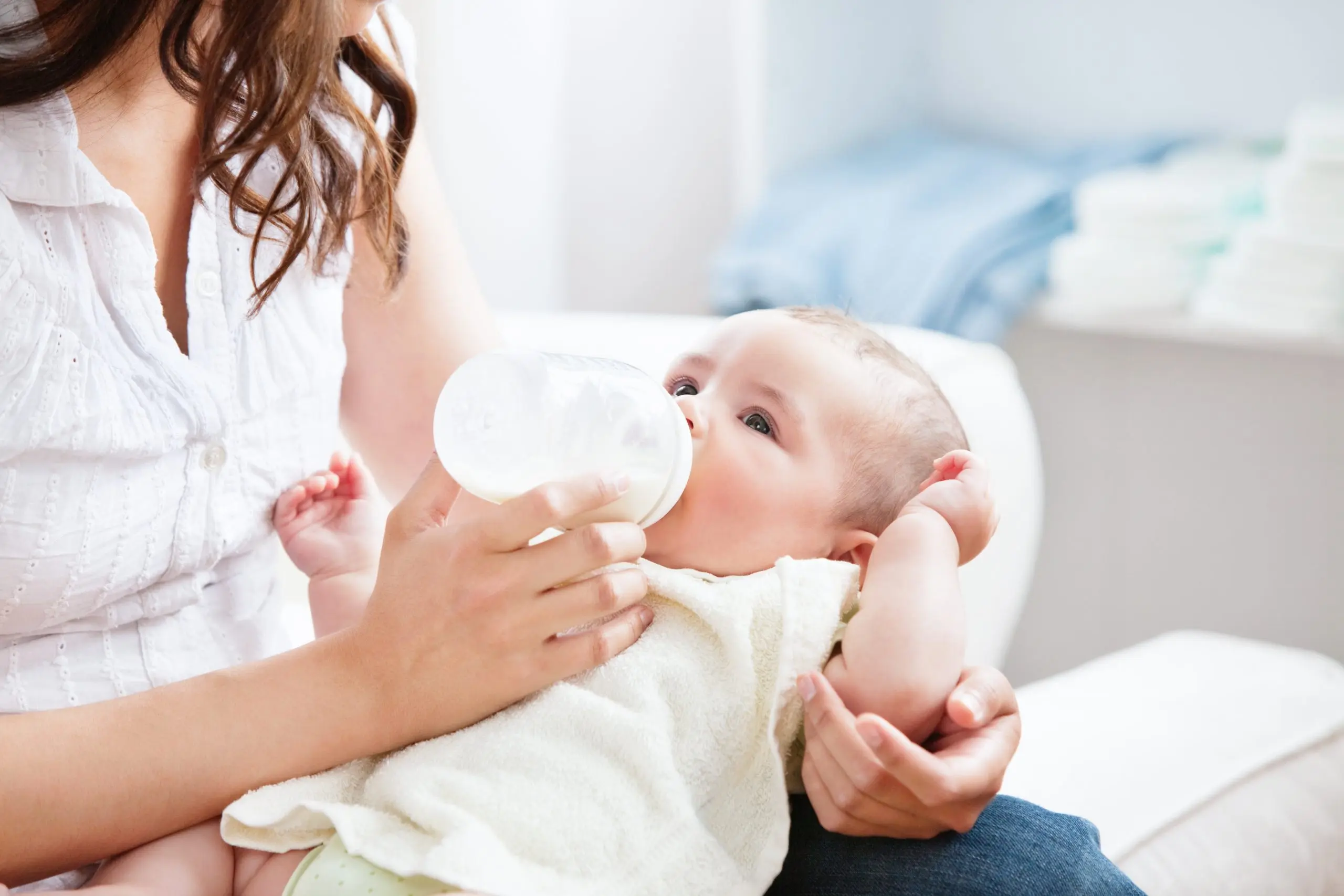 Mutter füttert Baby mit Fläschchen mit Säuglingsnahrung